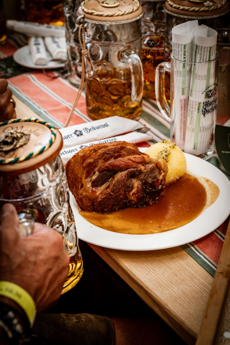 Schweinshaxe mit Kartoffelknödel und Sauce auf einem Tisch in der Bräurosl